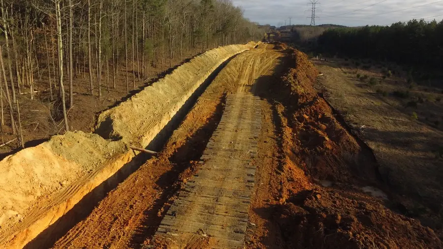 A pipeline right-of-way running cross-country toward transmission towers