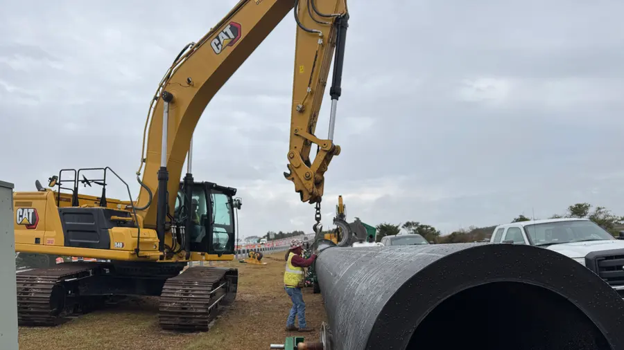 An excavator handling a section of large-diameter pipe