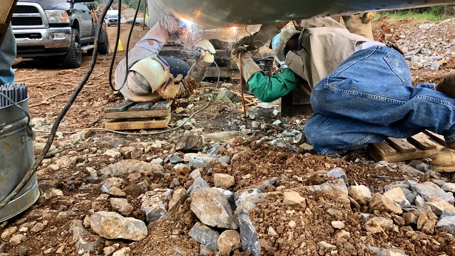 A crew working a pipeline tie-in in rocky ground
