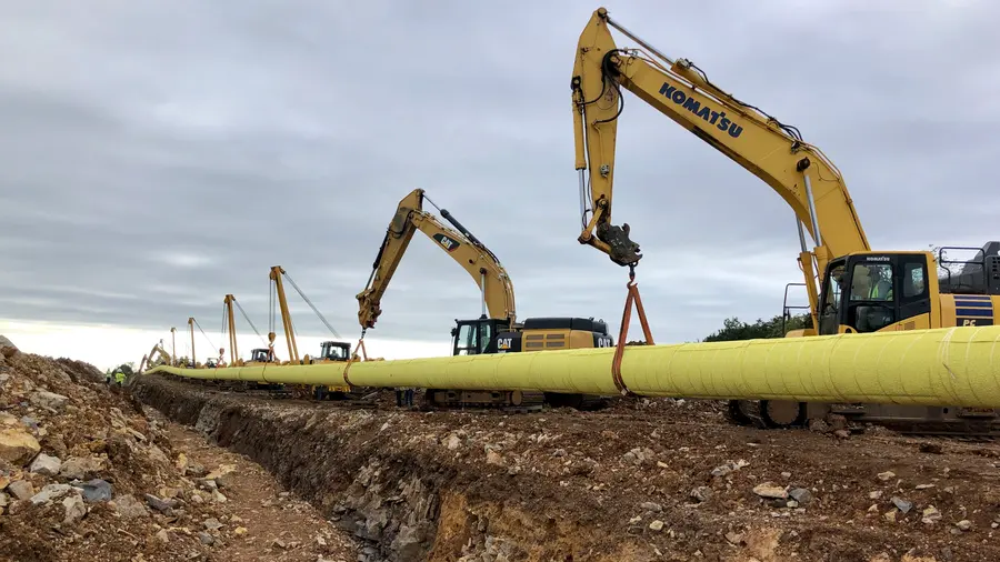 Sidebooms carrying a large-diameter pipeline over an open trench